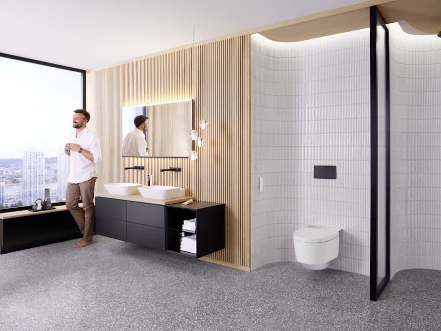 Mand i stort badeværelse med mørke møbler og Geberit AquaClean duschtoilet Mand i stort badeværelse med mørke møbler og Geberit AquaClean duschtoilet