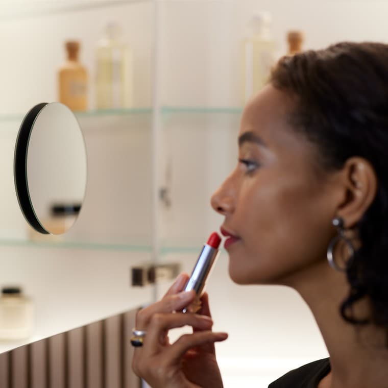 En kvinde bruger et spejl til at lægge makeup En kvinde bruger et spejl til at lægge makeup