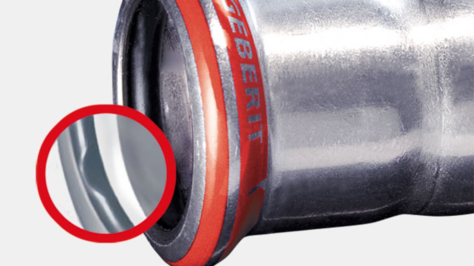 En Geberit Mapress El-Forzinket fitting med en rød presseindikator og sort o-ring En Geberit Mapress El-Forzinket fitting med en rød presseindikator og sort o-ring
